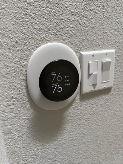 Nest thermostat installed beside the home's light controls